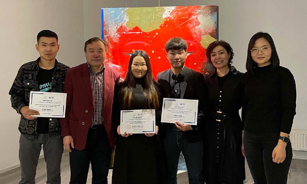 University students in Mongolia posing with their scholarship certificates while standing next to their professors