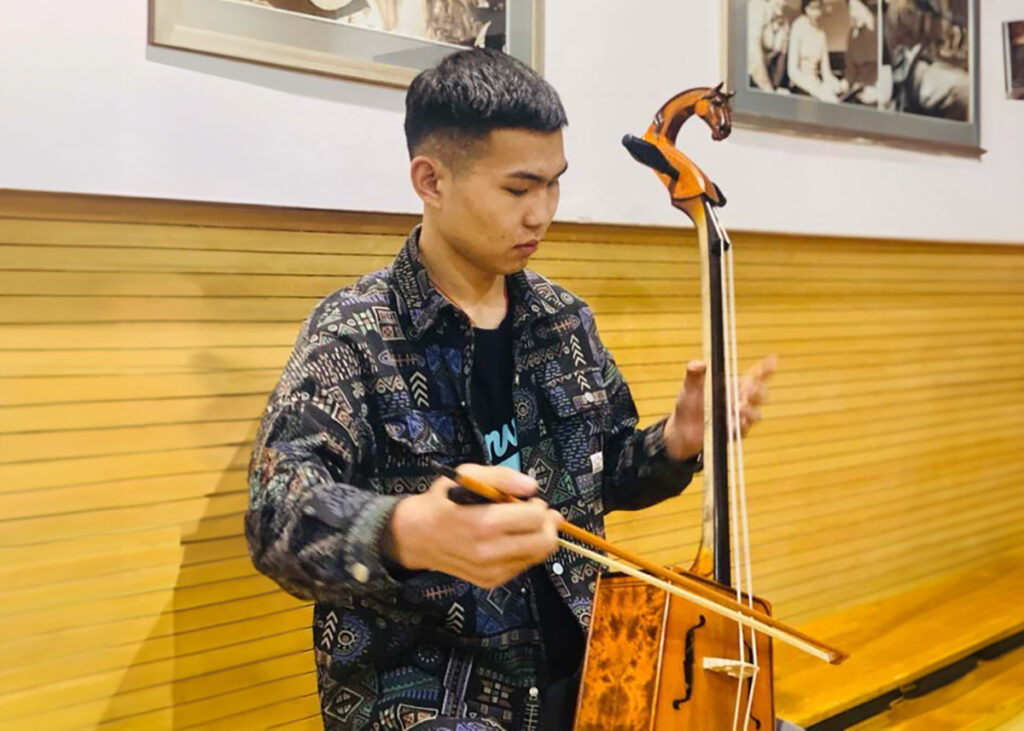 Mongolian male university student playing a string instrument