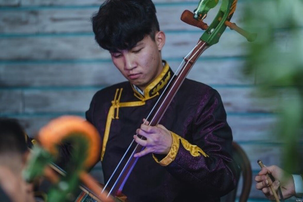 Mongolian male university student playing a string instrument