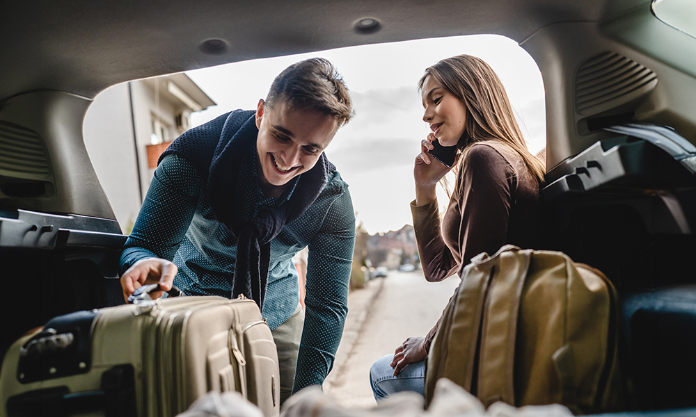 Man and woman packing their luggage into the trunk of a car